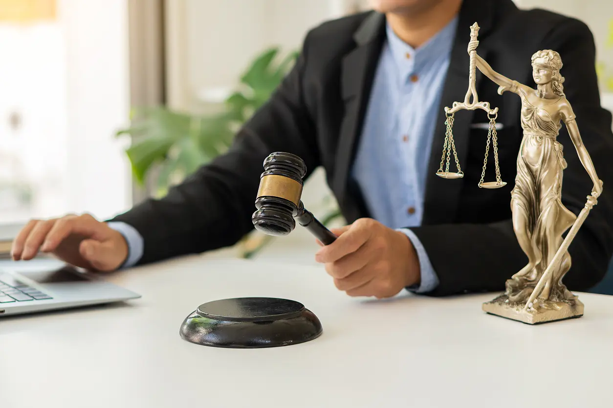 Judge with gavel and Lady Justice statue.