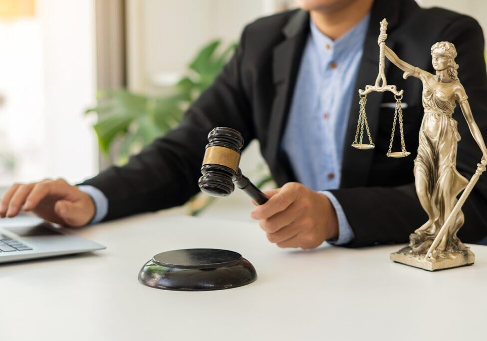 Judge with gavel and Lady Justice statue.